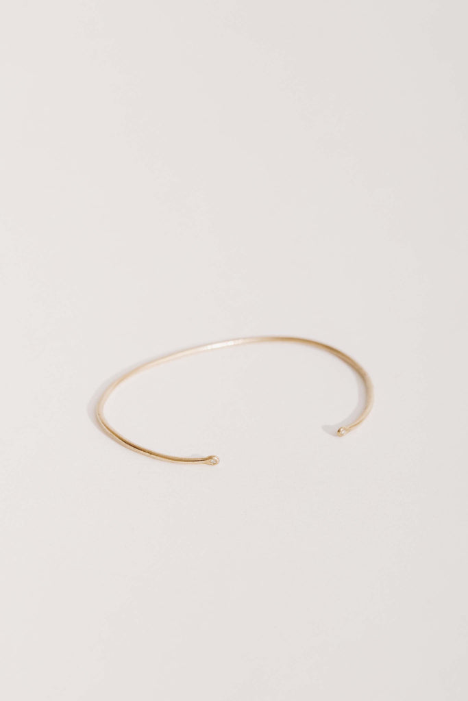 side view of thin gold cuff with small round diamonds on ends