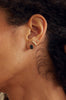 close up of woman wearing emerald cut blue sapphire gold stud alongside other gold earrings