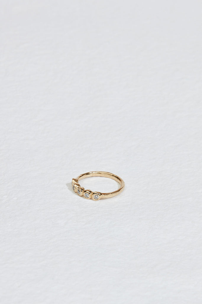 side view of gold ring with five bezel set round white diamonds