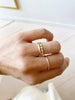 close up of hand wearing rounded gold band alongside other gold rings