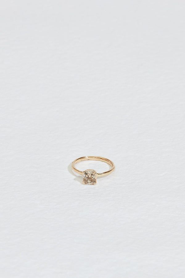 close up of four prong gold ring with cushion cut light champagne diamond