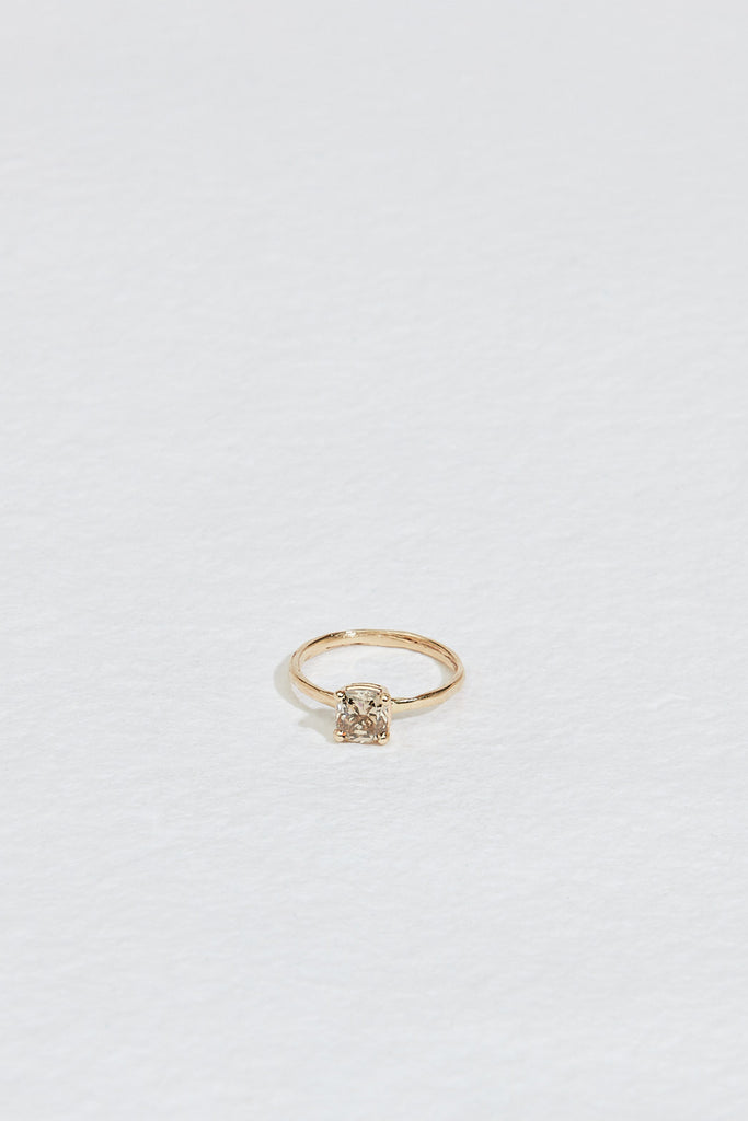 close up of four prong gold ring with cushion cut light champagne diamond