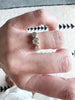 close up of hand wearing gold ring with three bezel set round white diamonds