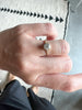 close up of hand wearing gold ring with bezel set round white diamond