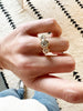 close up of hand wearing gold ring with three bezel set round white diamonds