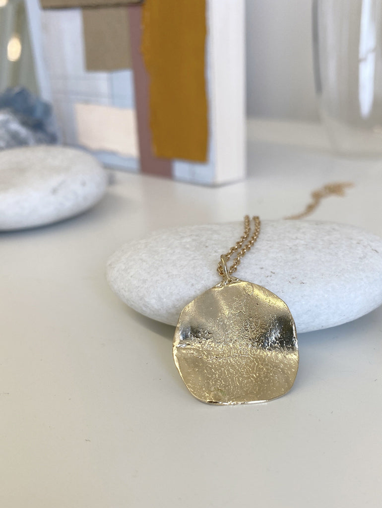 close up of gold necklace with engraved dog print
