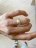 close up of hand wearing yellow gold cigar band with five scattered round white diamonds