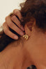 close up of woman wearing gold three prong earring