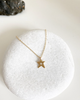 close up of gold necklace and gold star with round white diamond