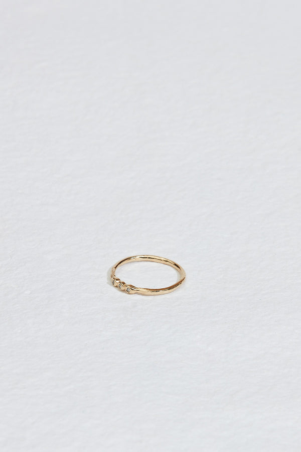 side view of thin gold band with three bezel set round white diamonds