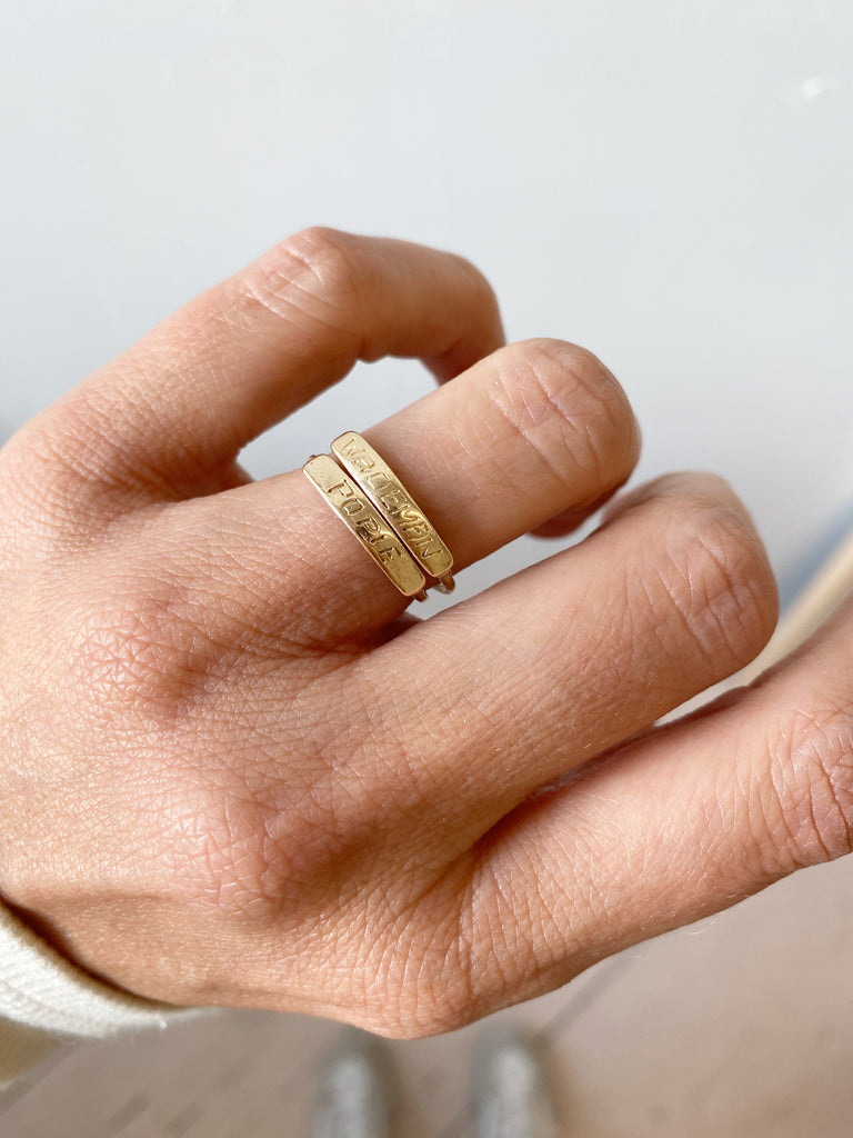 close up of hand wearing two gold rings with hand engraved front plates