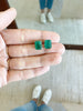 close up of hand holding gold emerald cut emerald studs