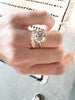 close up of hand wearing gold ring with decagon bezel set round brilliant diamond alongside diamond band