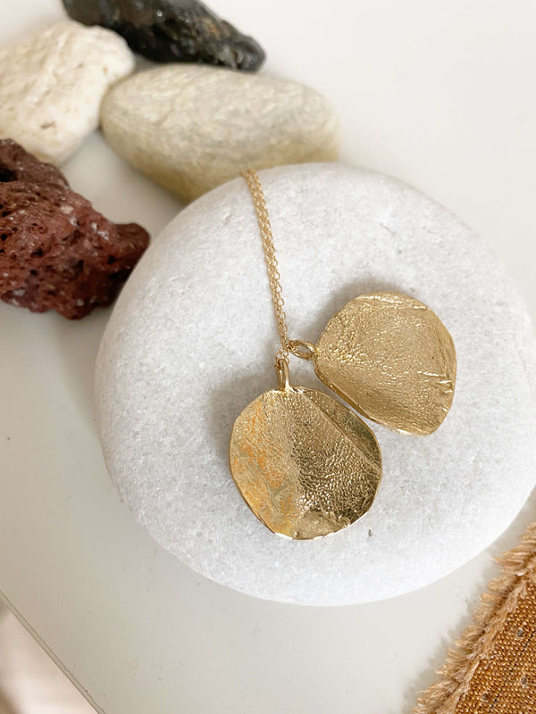close up of gold necklace with two engraved dog print discs