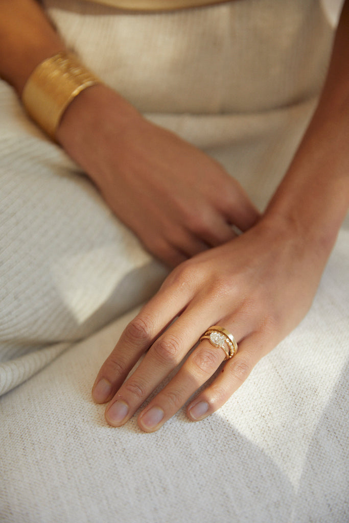 woman wearing gold band with straight sides alongside other gold jewelry