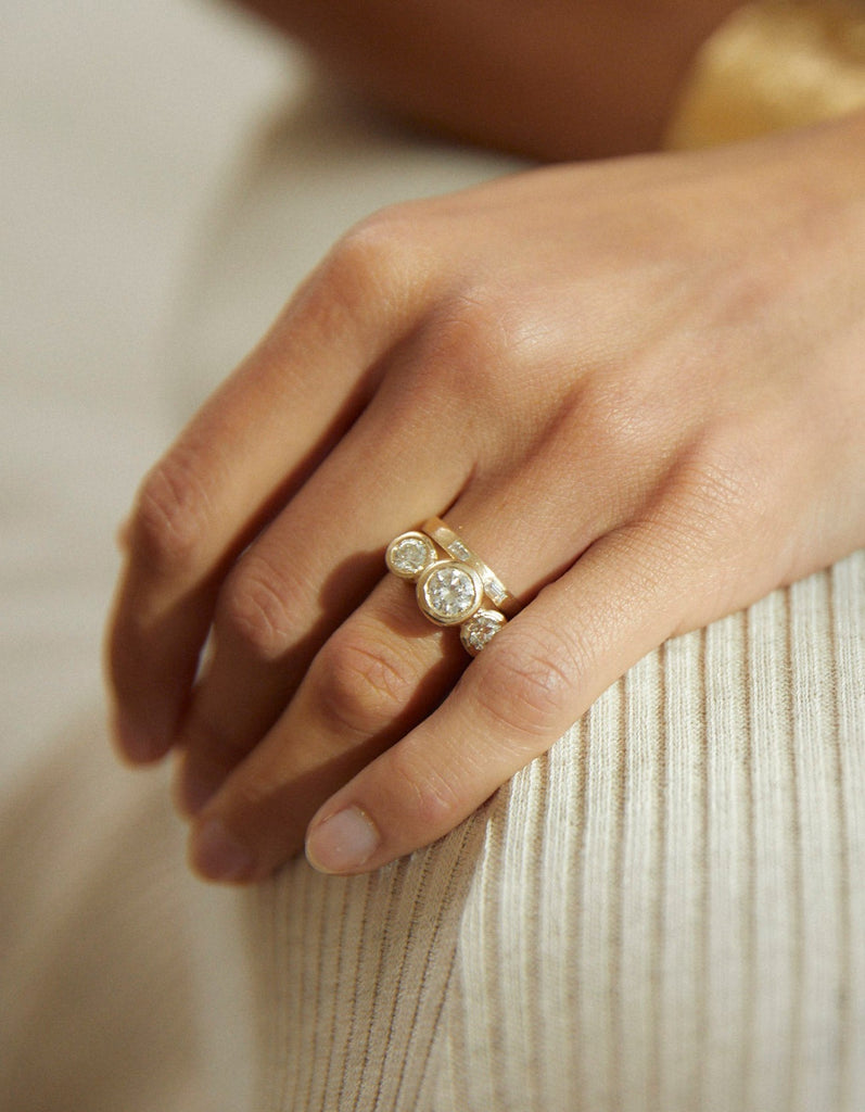 close up of gold ring with three bezel set round white diamonds alongside gold band